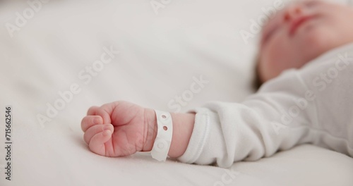 Baby, new born and hand with bracelet on bed for care, trust or support in hospital for birth. Infant, love and hope with child development for future growth in family home, protection and security photo