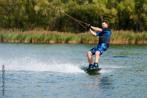 a male wakeboarder rides on water with splashes