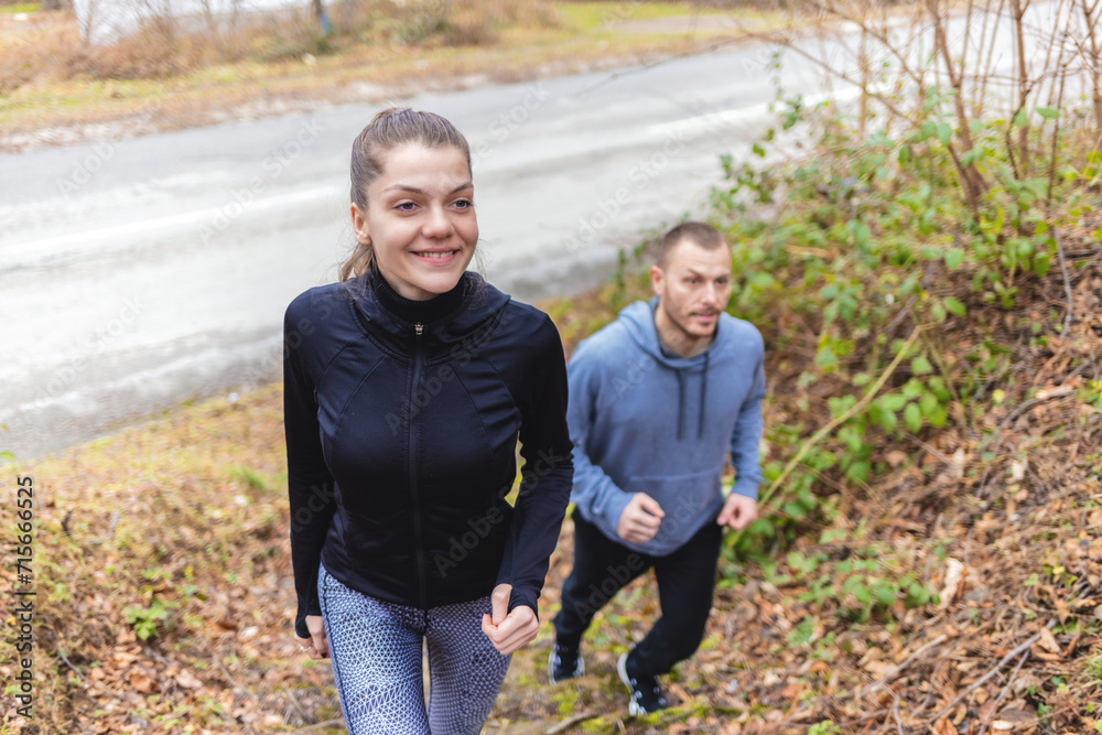 Fototapeta premium Happy Caucasian couple having fun while running in the nature in autumn day. Copy space.
