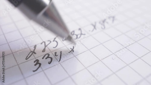 Solving a math problem on a sheet of paper with ballpoint pen, close-up view photo