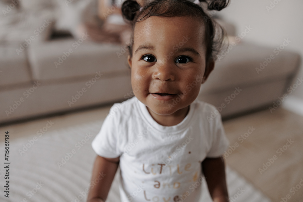 © Stanislav - Portrait of joyful mixed race toddler girl in room.