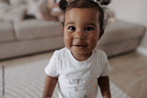 Portrait of joyful mixed race toddler girl in room. photo