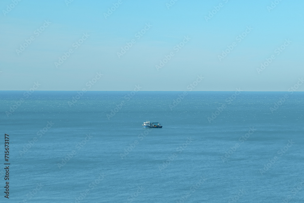 ship goes into the horizon of the blue sea, leaving a trail on the surface of the water landscape. Aerial view, concept of sea travel, cruises.