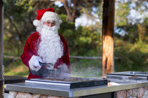 santa cooking sausages and lamb chops on a bbq in a park photo