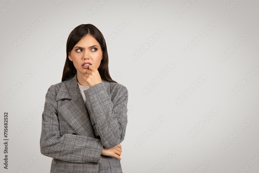 Woman in plaid blazer pondering, looking sideway at free space Woman in plaid blazer pondering, looking sideway at free space