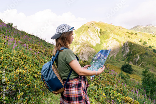 Young woman tourist and traveler with a map in her hands in a mountain valley. Hiking and active lifestyle