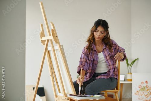 Creative zoomer girl in plaid shirt painting picture on canvas photo