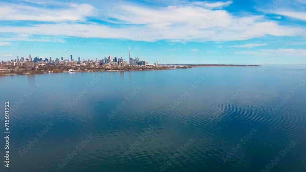 North American city beside lake, clear day, epitomizes business life. Business life thrives cityscape, lake shimmering under clear sky. Vibrant business life lakefront city, clear day. Drone view.