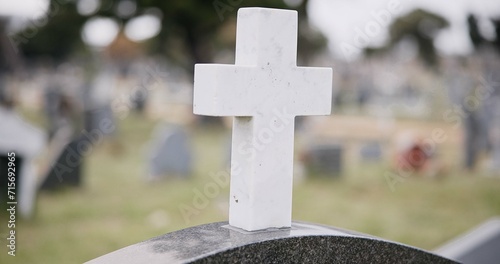 Funeral, graveyard and cross on tombstone for death ceremony, religion or memorial service. Catholic symbol, background or Christian sign on gravestone for mourning, burial or loss in public cemetery