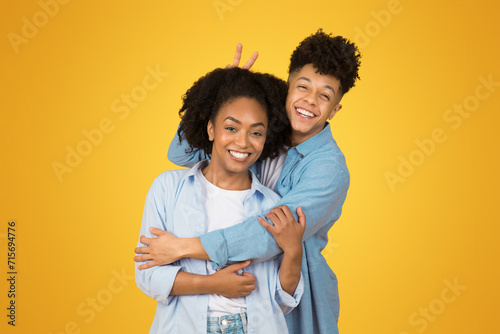 A playful young couple enjoys a fun moment, with one giving the other bunny ears photo