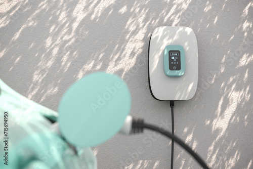 Charging an electric vehicle at home with a home charging station (wallbox). Focus on the wallbox displaying status information. Leaves casting shadows onto the wall. Selective focus.