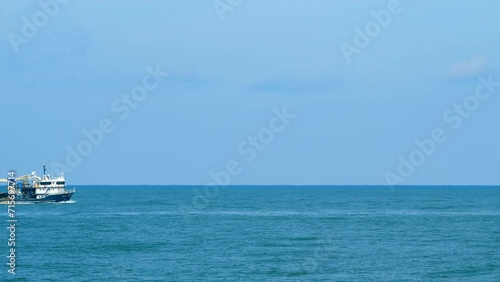 Fishing Boat On The Horizon At Sea. Abstract Small Waves On Calm Water Surface In Motion. Real time. photo