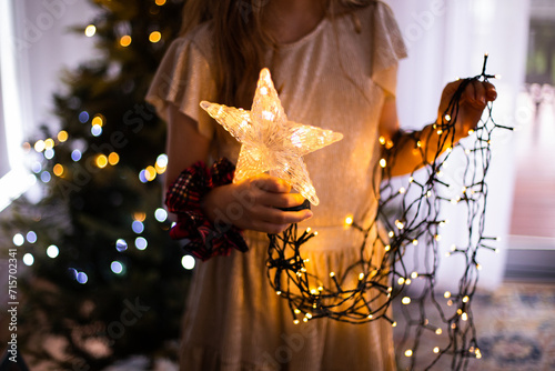 girl holding christmas tree star and strings of lights photo