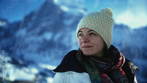Contemplative 30s woman enjoying cold season view from high above in the mountains. Meditative person wearing beanie and scarf portrait