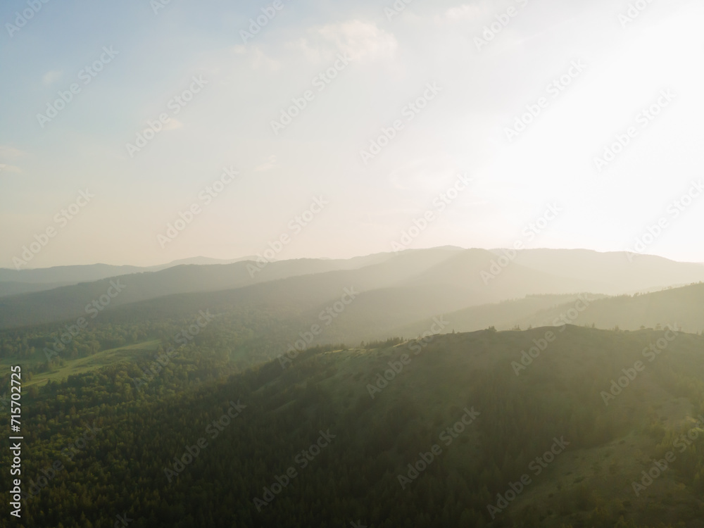 Aerial top view beautiful high mountains in the rays of the sun at sunset against a clear blue sky. Nature reserve, ecopark. Nature background. Photo from the drone.