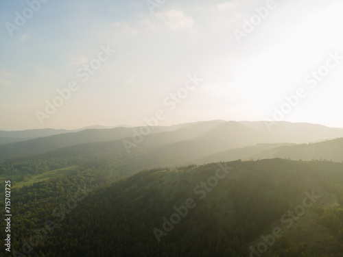 Aerial top view beautiful high mountains in the rays of the sun at sunset against a clear blue sky. Nature reserve  ecopark. Nature background. Photo from the drone.
