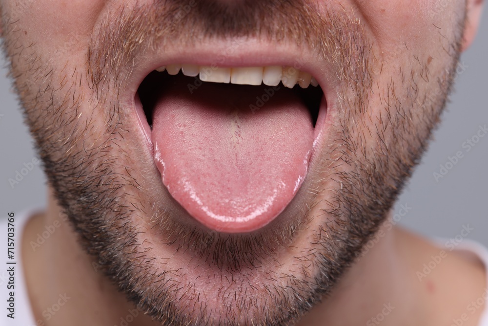 Closeup view of man showing his tongue on grey background