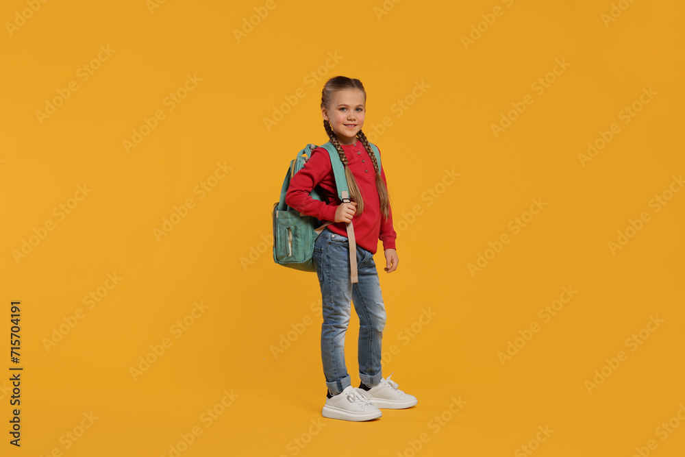 Happy schoolgirl with backpack on orange background Happy schoolgirl with backpack on orange background