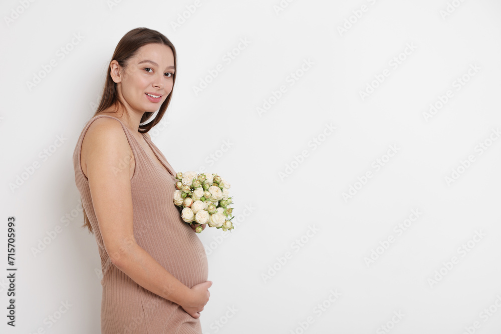 Beautiful pregnant woman in beige dress with bouquet of roses on white background, space for text Beautiful pregnant woman in beige dress with bouquet of roses on white background, space for text