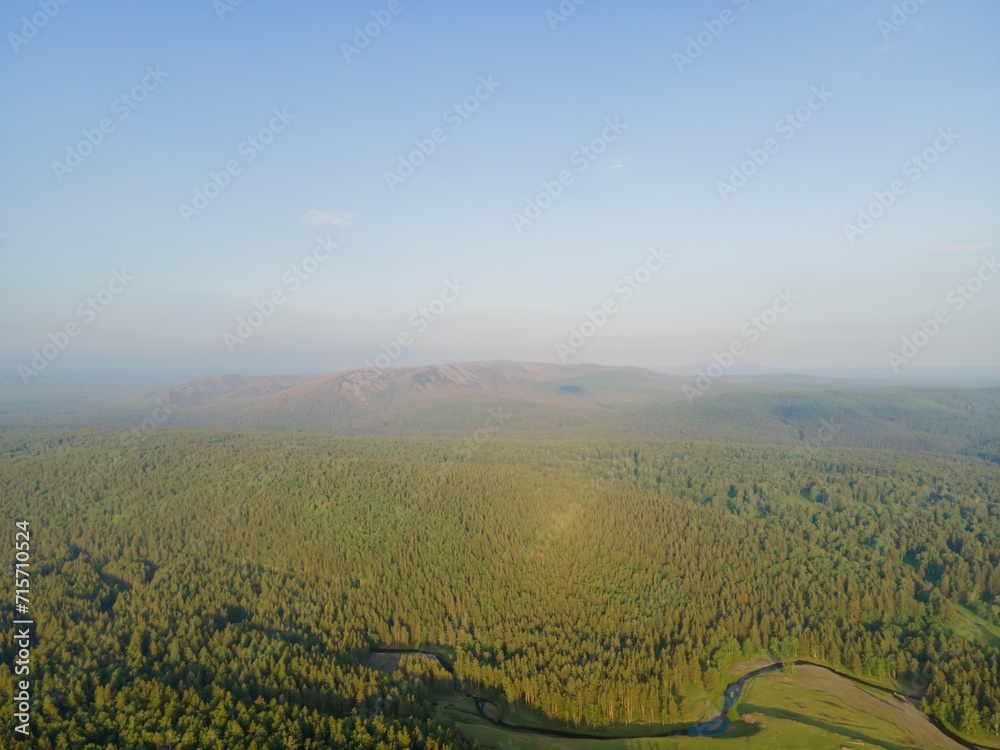 A beautiful evening sunrise landscape. Aerial view of beautiful green pine forests against a blue sky background at sunset. Nature background. Photo from the drone.