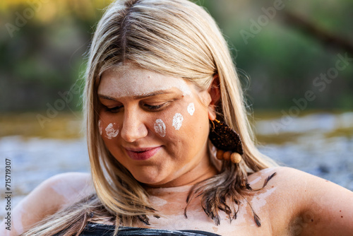 Aboriginal woman looking down in traditional ochre paint photo