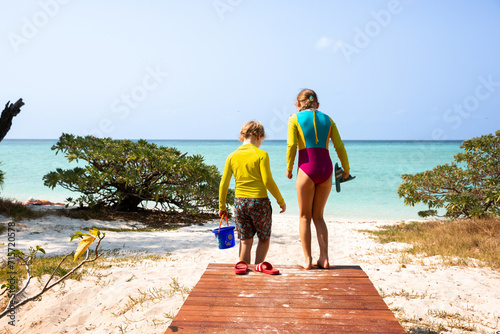 children stepping from the boardwalk to the sand of Heron Island beach photo