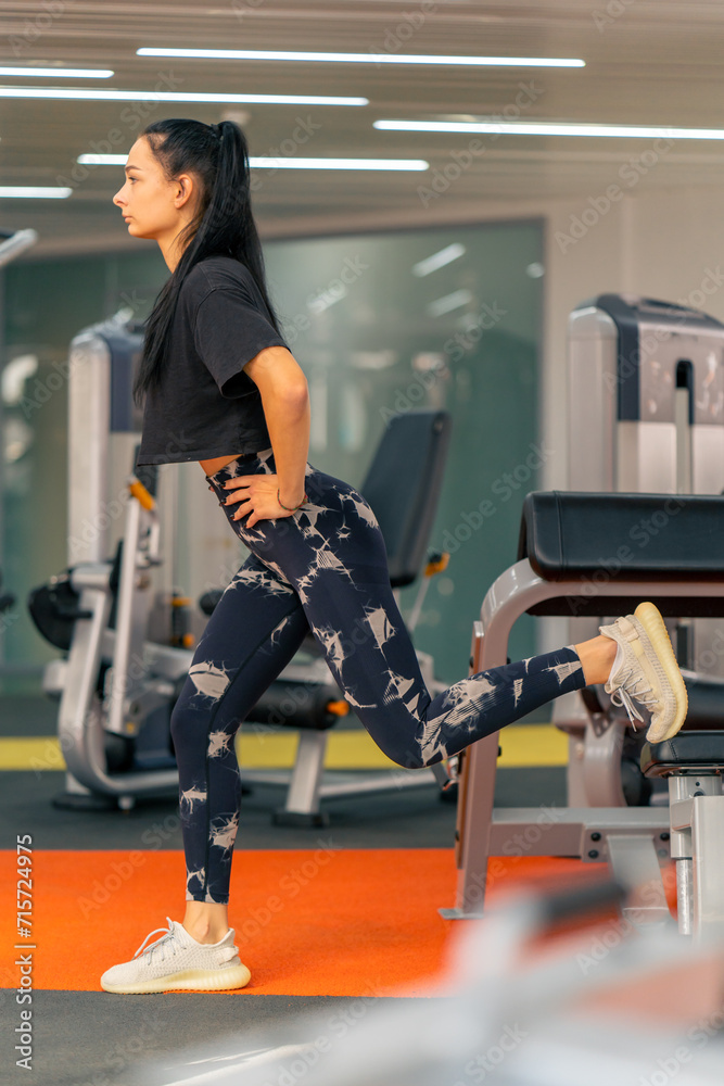 young girl in sportswear in the gym doing squats during fitness training healthy beautiful body