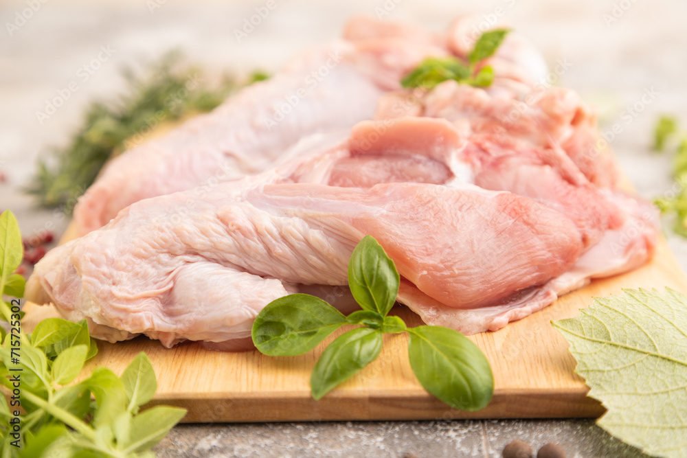 Raw turkey wing on a wooden cutting board on a brown concrete background. Side view, selective focus Raw turkey wing on a wooden cutting board on a brown concrete background. Side view, selective focus