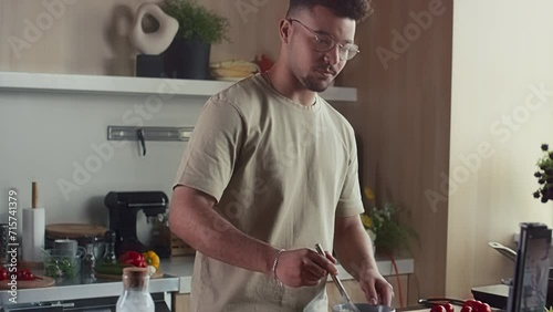 Food blogger whisking ingredients in bowl and telling how to cook breakfast while filming video recipe with mobile phone on tripod in kitchen photo