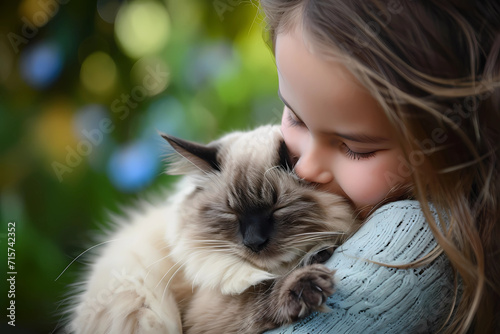 A young girl finds solace and joy as she tenderly cuddles with her Balinese cat, a poignant display of profound companionship and an unspoken bond filled with genuine love and mutual affection