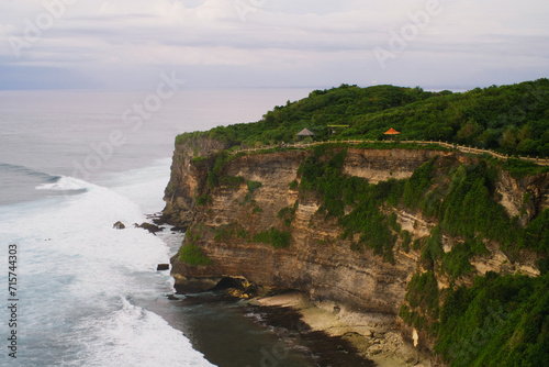 Portrait of beautiful Uluwatu beach scene with cliff, rocks and sea waves in afternoon 