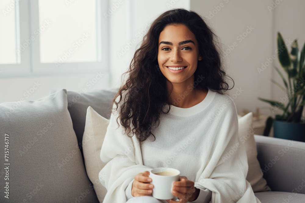 Latin woman drinking coffee sitting on sofa at home