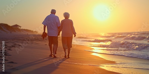 A joyful elderly couple walking on the beach enjoying a leisurely sunset photo