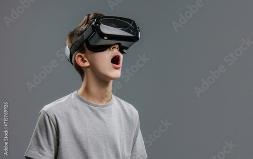 Surprised teen student in VR glasses explores virtual space. © OLGA