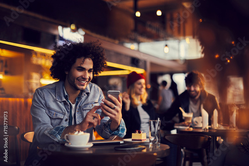 Smiling young man using smartphone in a cafe photo