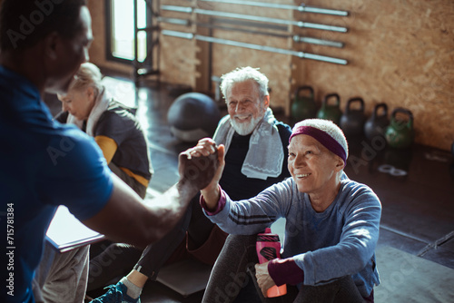 Diverse senior people working out with trainer in gym photo