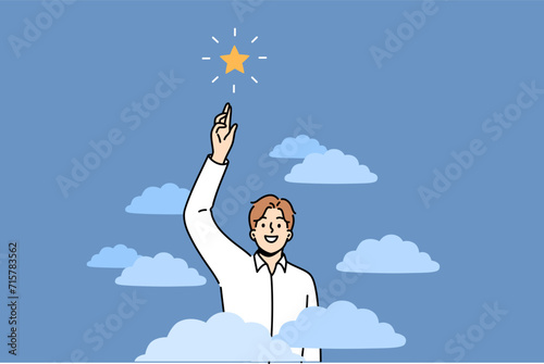 Business man shows ambition by trying to reach star from sky, showing leadership and lack of fear. Guy with ambition feels confidence to achieve success in career and personal life.