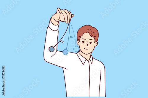 Man hypnotist with swinging pendulum in hand makes suggestion to patient or helps restore memory of forgotten event. Guy is hypnotist brainwashes people into believing facts that dont exist.