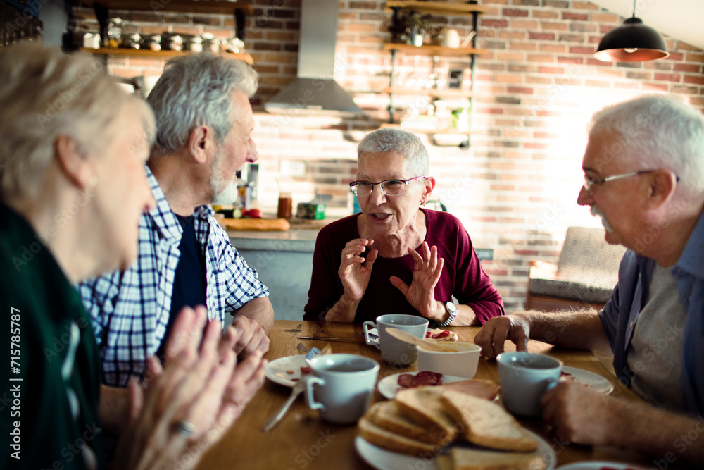 Group of senior friends enjoying conversation and breakfast together