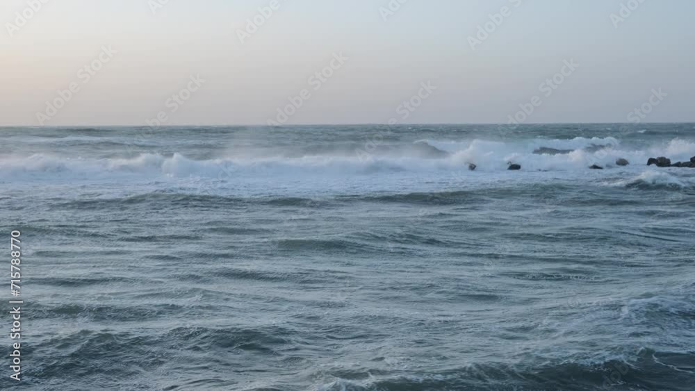 Large waves in the Mediterranean Sea crash against the rocks, depicting a scene of stormy weather at sea. Large waves in the Mediterranean Sea crash against the rocks, depicting a scene of stormy weather at sea.