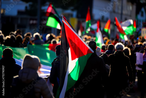 waving Palestinian flags with unidentifiable backlit protesters during the peaceful demonstration for peace photo
