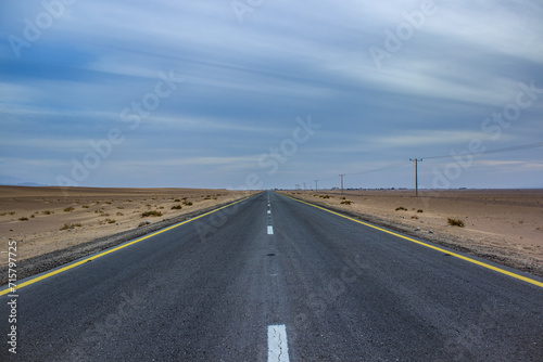 drive in desert on straight asphalt road idyllic simple wallpaper concept country side dramatic picture with cloudy weather and sand environment