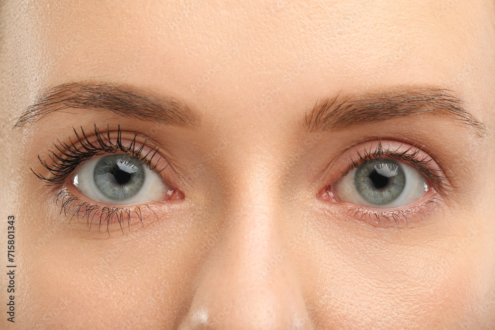 Obraz premium Woman showing difference in eyelashes length after mascara applying, closeup
