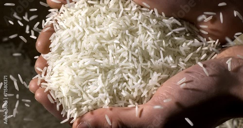 Super slow motion macro of farmer is controlling quality of handful dry basmati quality white rice over burlap sack background at 1000 fps.
