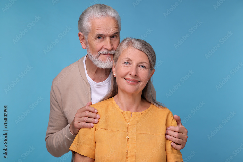 Portrait of affectionate senior couple on light blue background Portrait of affectionate senior couple on light blue background