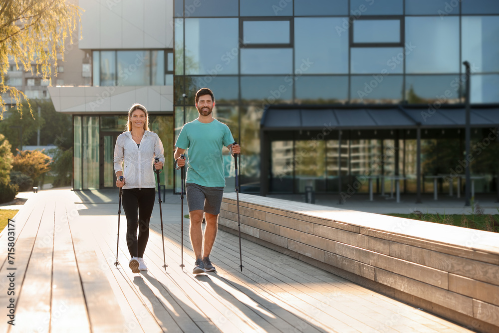 Happy couple practicing Nordic walking with poles outdoors Happy couple practicing Nordic walking with poles outdoors