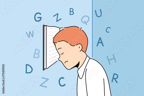 Boy with school textbook, tired due to grueling lessons and difficult homework, stands with head resting on book. Primary school student needs rest to avoid overexertion and depression.