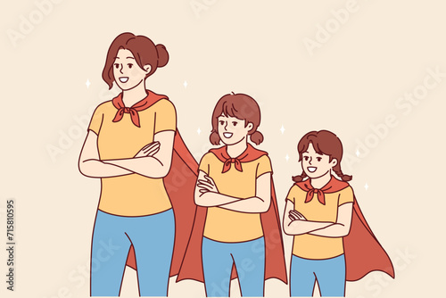 Mom and daughters in superhero capes smile, feeling unity and courage, stand with arms crossed. Girls of different generations dressed up as superwomen for costume festival for comic book fans