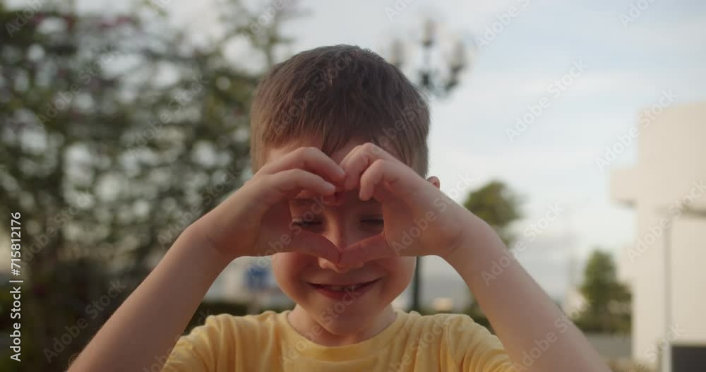 Beautiful happy little cute child face adorable boy kid seen through joined fingers making heart shape, close up. Symbol of love, cherish, family bonding, donation sign, adoption and custody. 4K