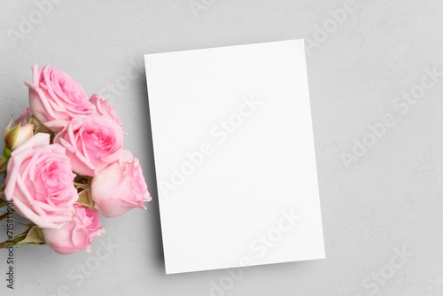 Blank invitation card mockup with roses flowers on grey background © nikavera